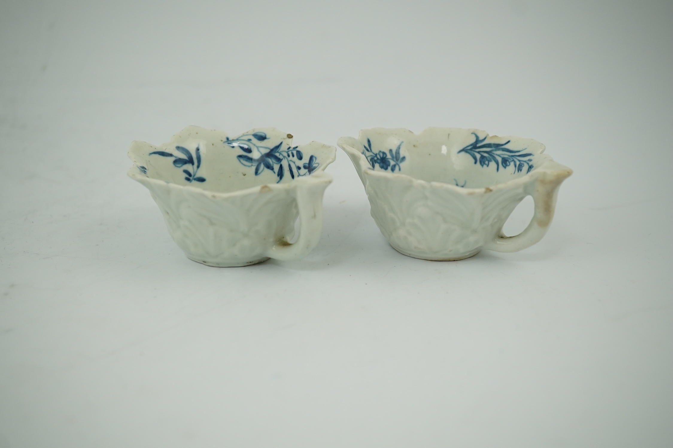 A pair of Worcester blue and white butterboats, c.1758-60, with differing blue and white decoration, 8cm wide. Condition - fair, some chips commensurate with age, one cracked.